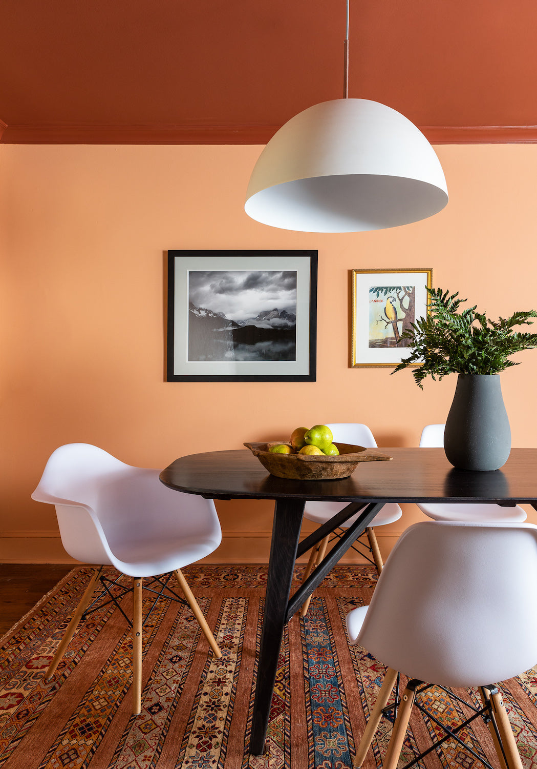 A dining area in shades of orange and rust with modern furnishings, designed by Lisa & Leroy.