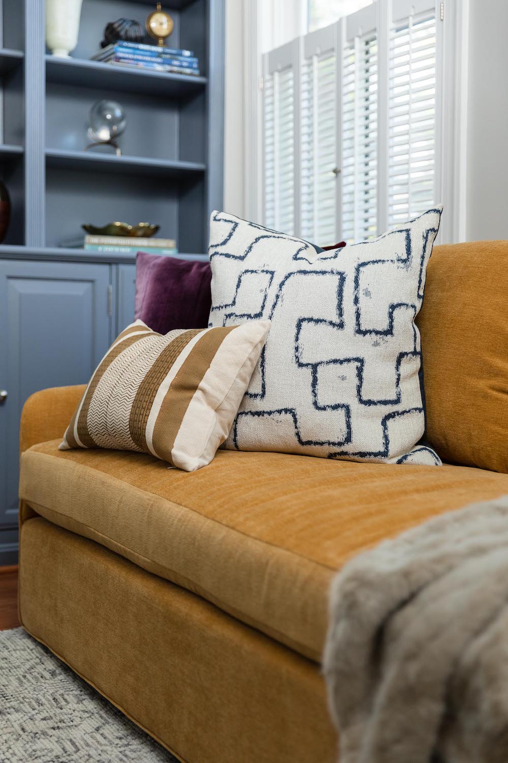 A living area by Lisa & Leroy, featuring dusty blue built-ins and a yellow sofa.