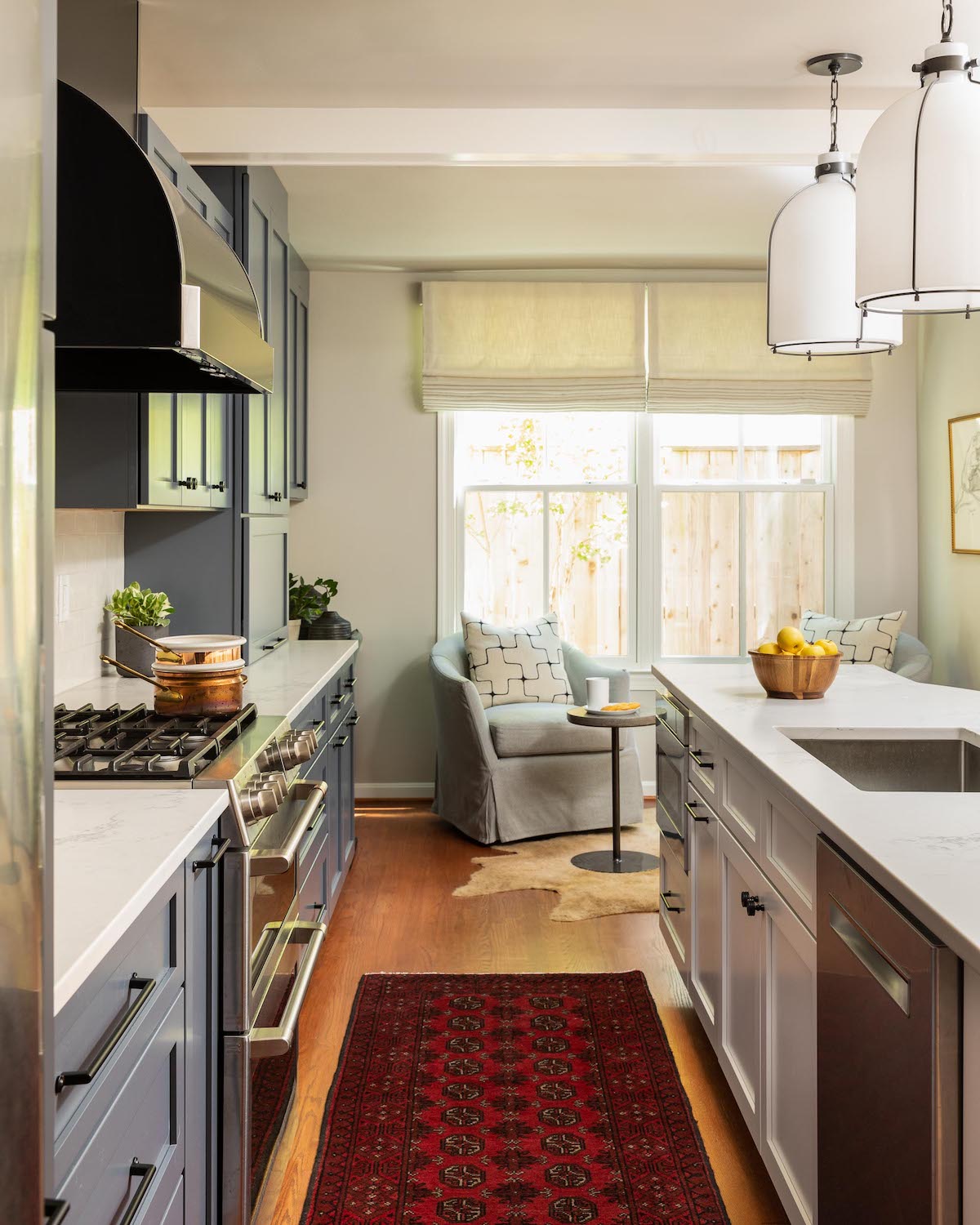 A kitchen with dusty blue cabinetry, a vintage runner, and ceramic tile by Lisa & Leroy.
