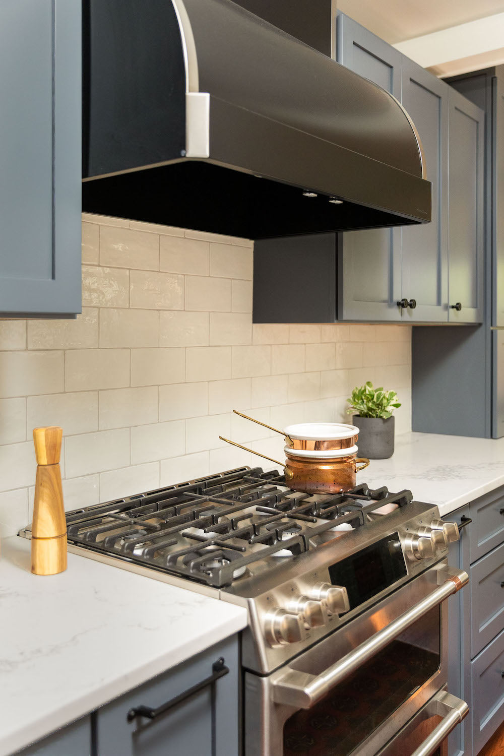A kitchen with dusty blue cabinetry and ceramic tile by Lisa & Leroy.