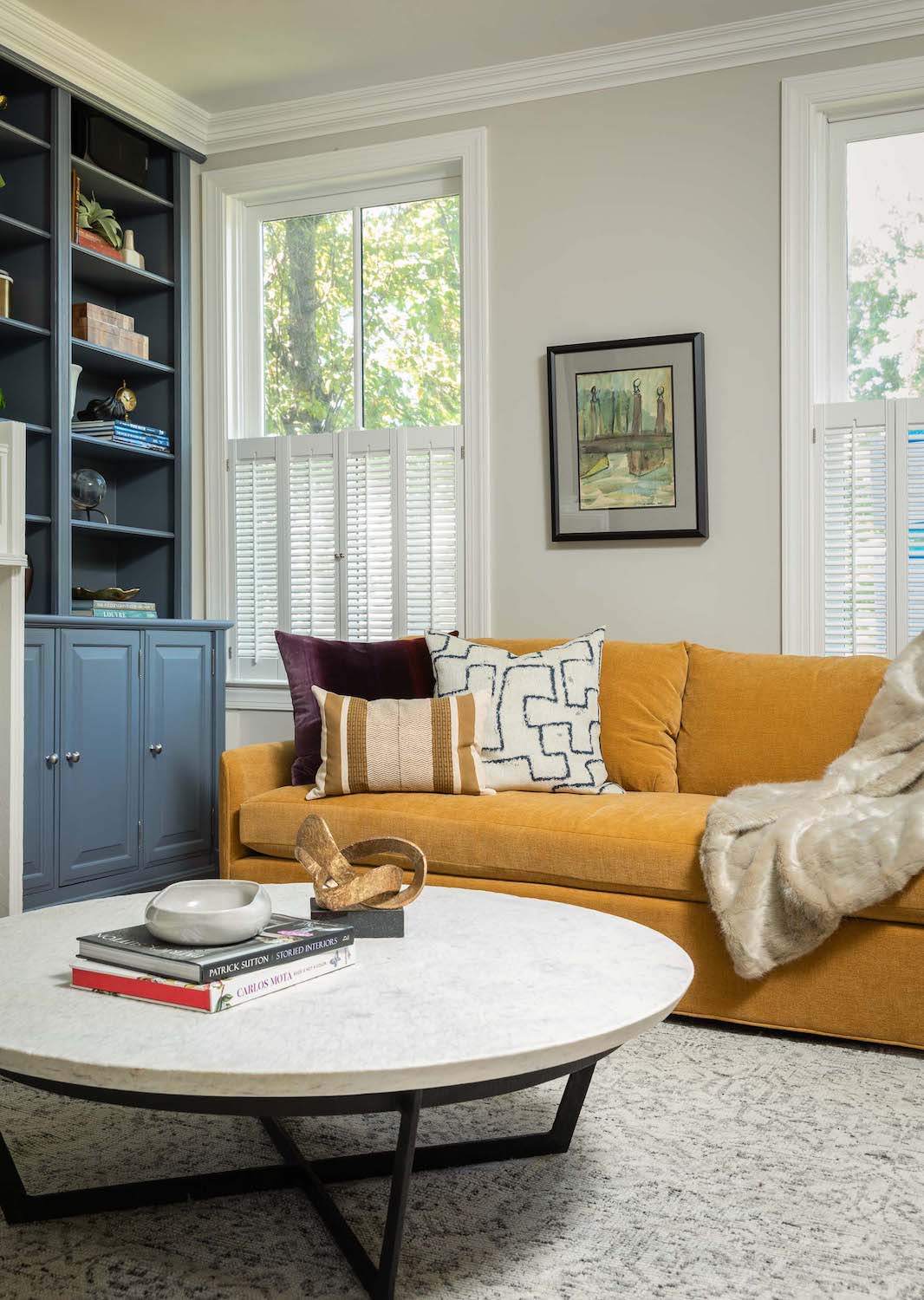 A living area by Lisa & Leroy, featuring dusty blue built-ins and a yellow sofa.