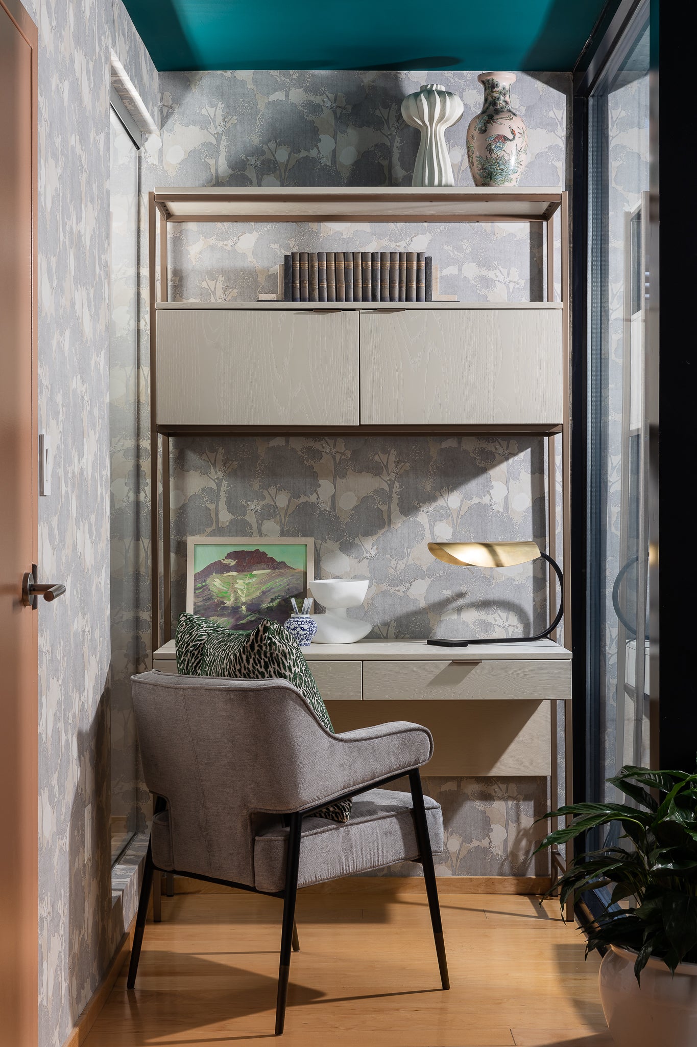 A home working space with pattered wallpaper and a modern upholstered chair, by Lisa & Leroy.