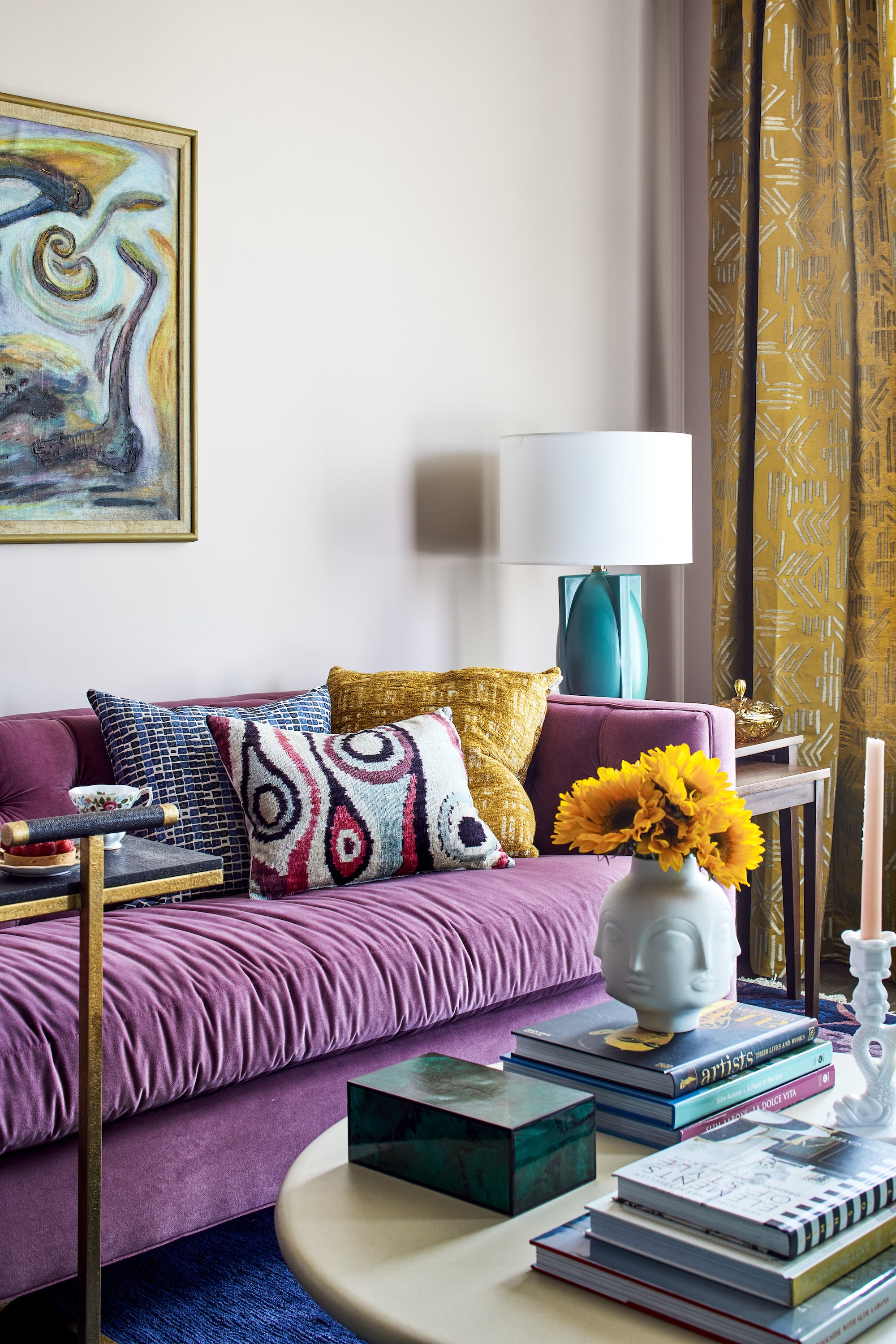 A funky yet elevated sitting area with a purple couch and abstract art by Lisa & Leroy.