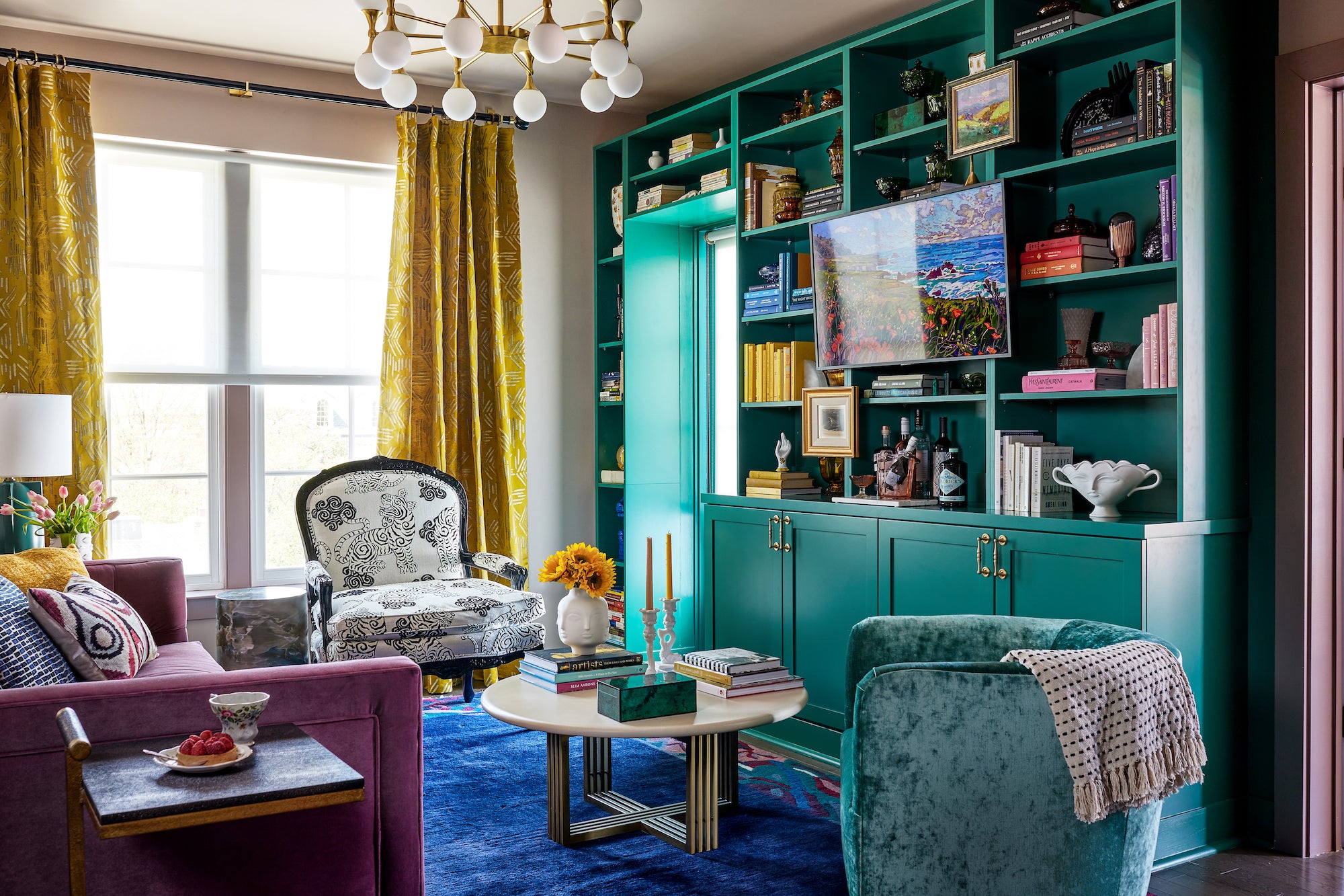 A jewel-toned sitting area with colorful books, art, and textiles by Lisa & Leroy.