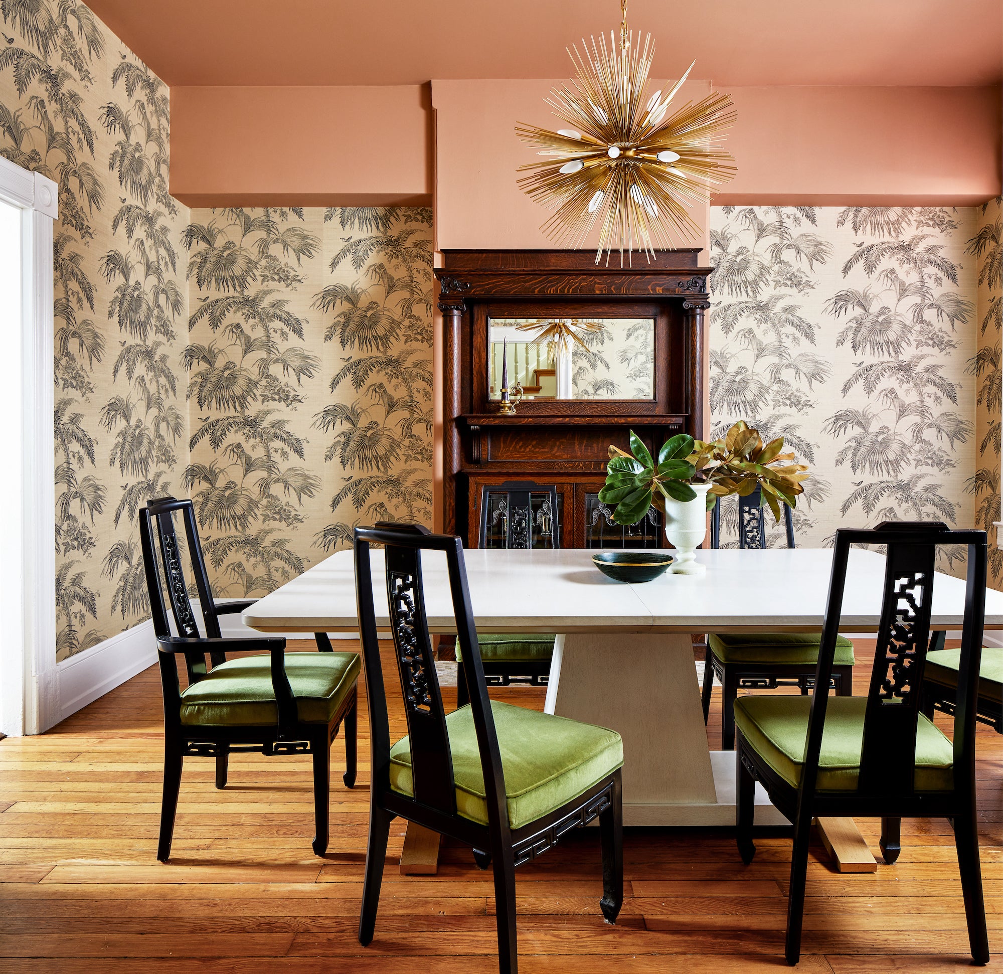 A wallpapered dining area with a white table and original fireplace by Lisa & Leroy.