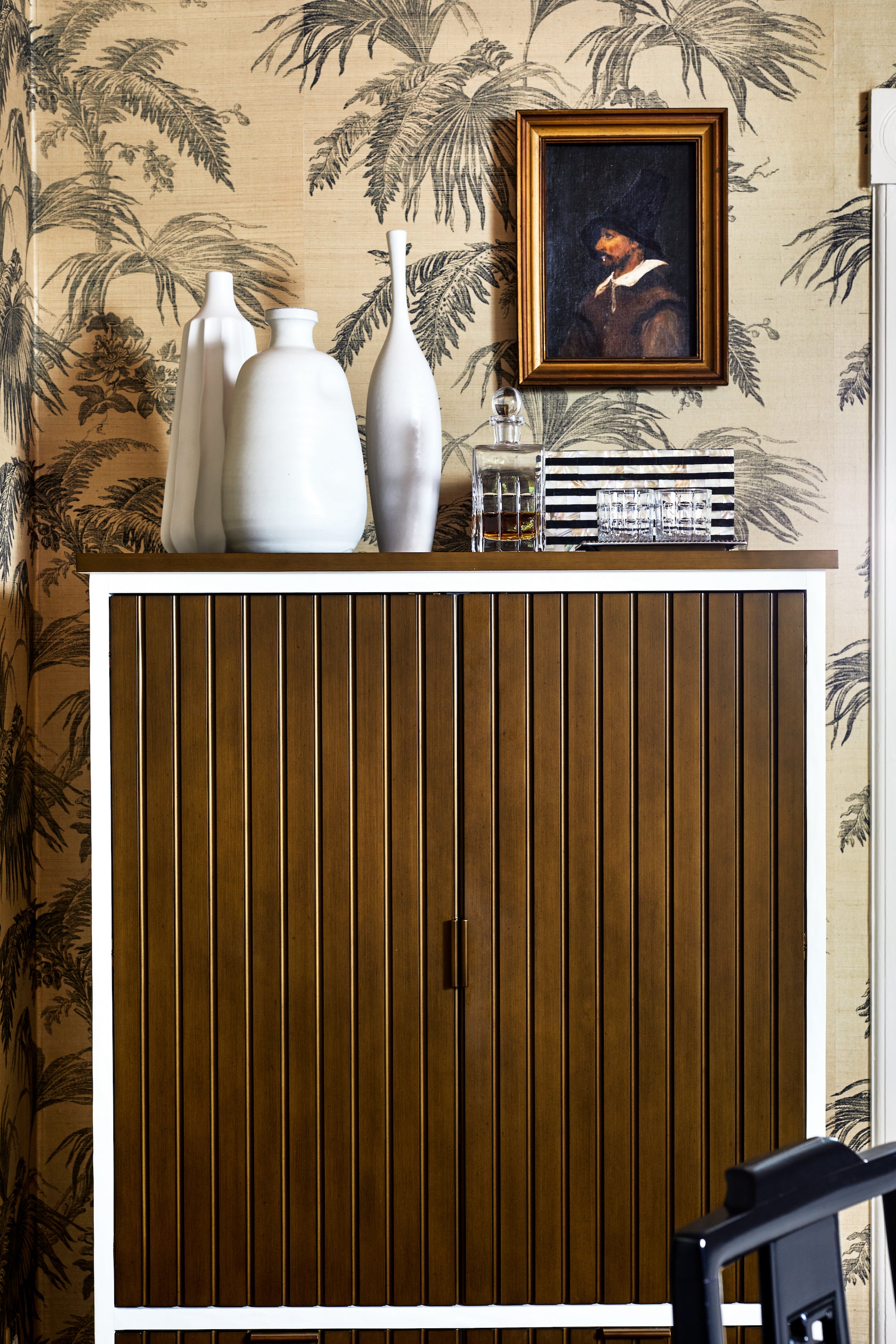 A paneled cabinet in a wallpapered dining room by Lisa & Leroy.