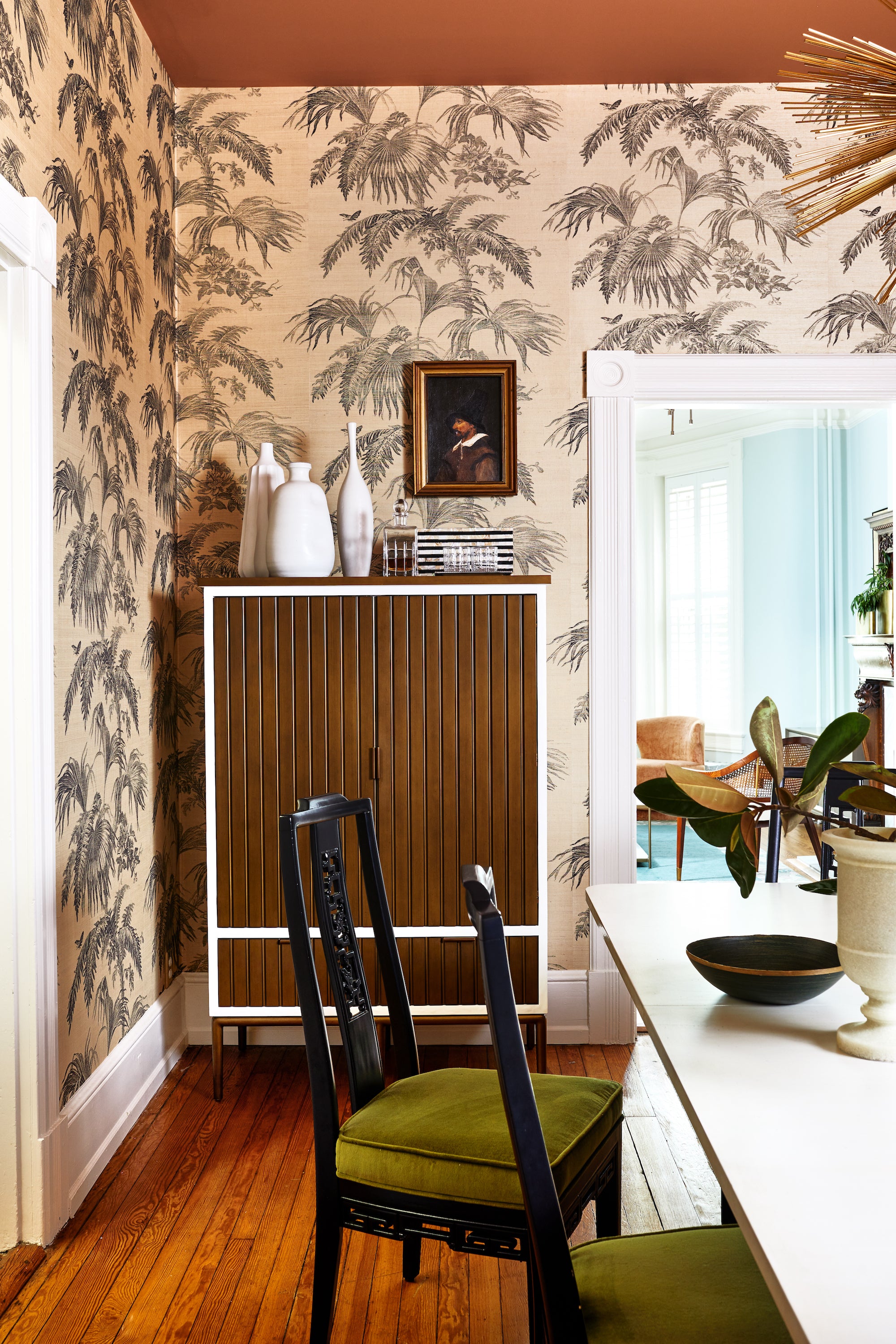 A wallpapered dining area with a white table and original fireplace by Lisa & Leroy.