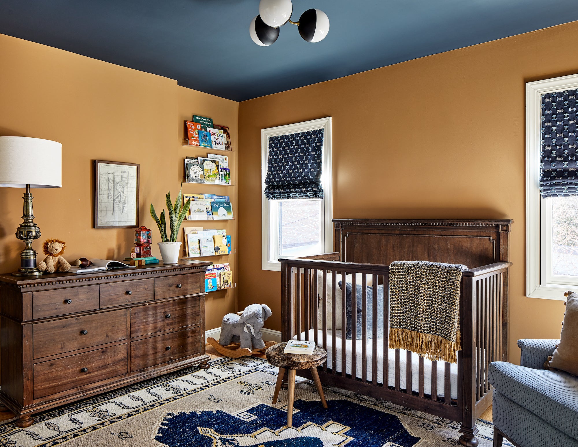 A playful nursery with earth tones, warm woods, and accents of blue, by Lisa & Leroy.