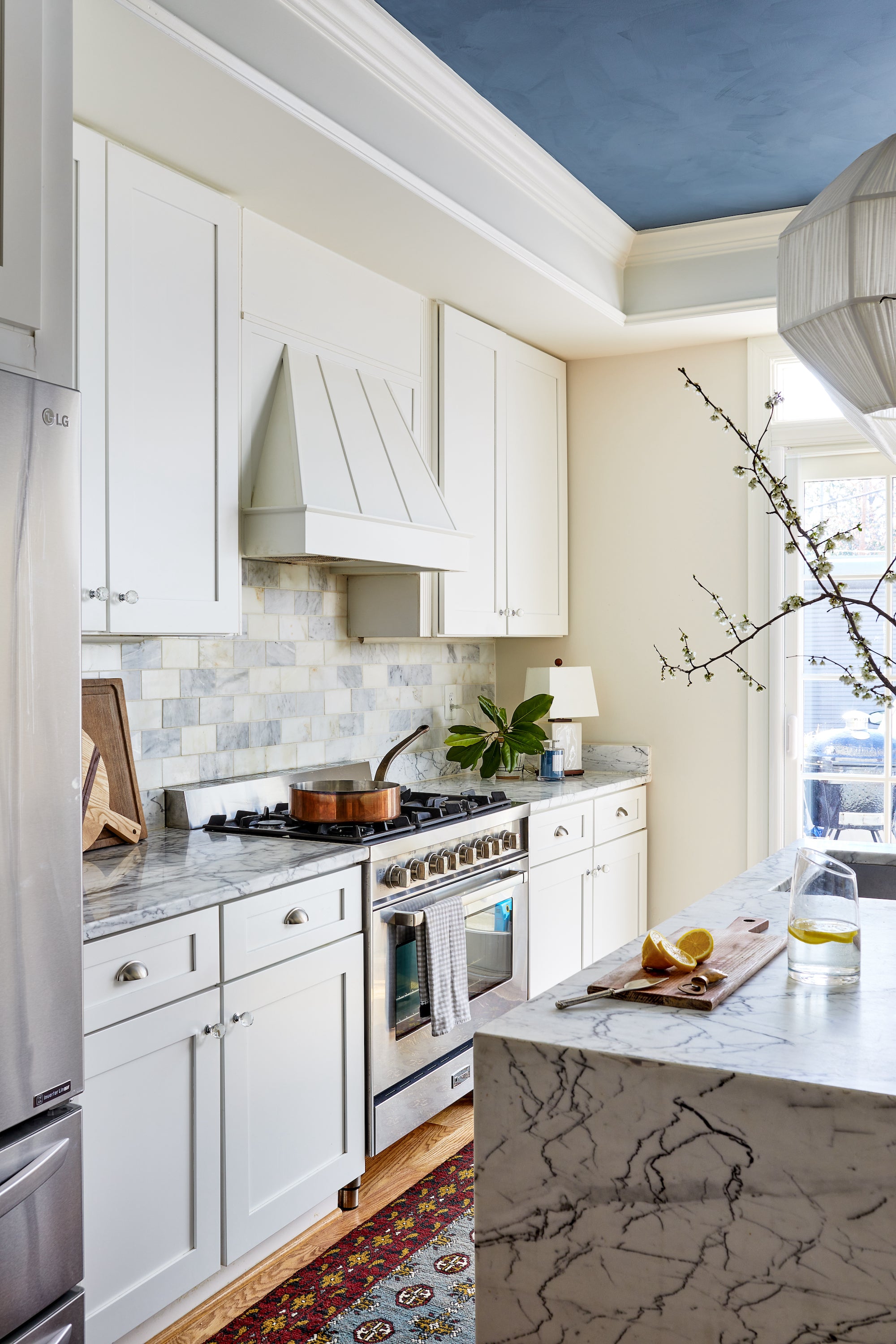 A kitchen by Lisa & Leroy, with veiny marble and ceramic tiles.