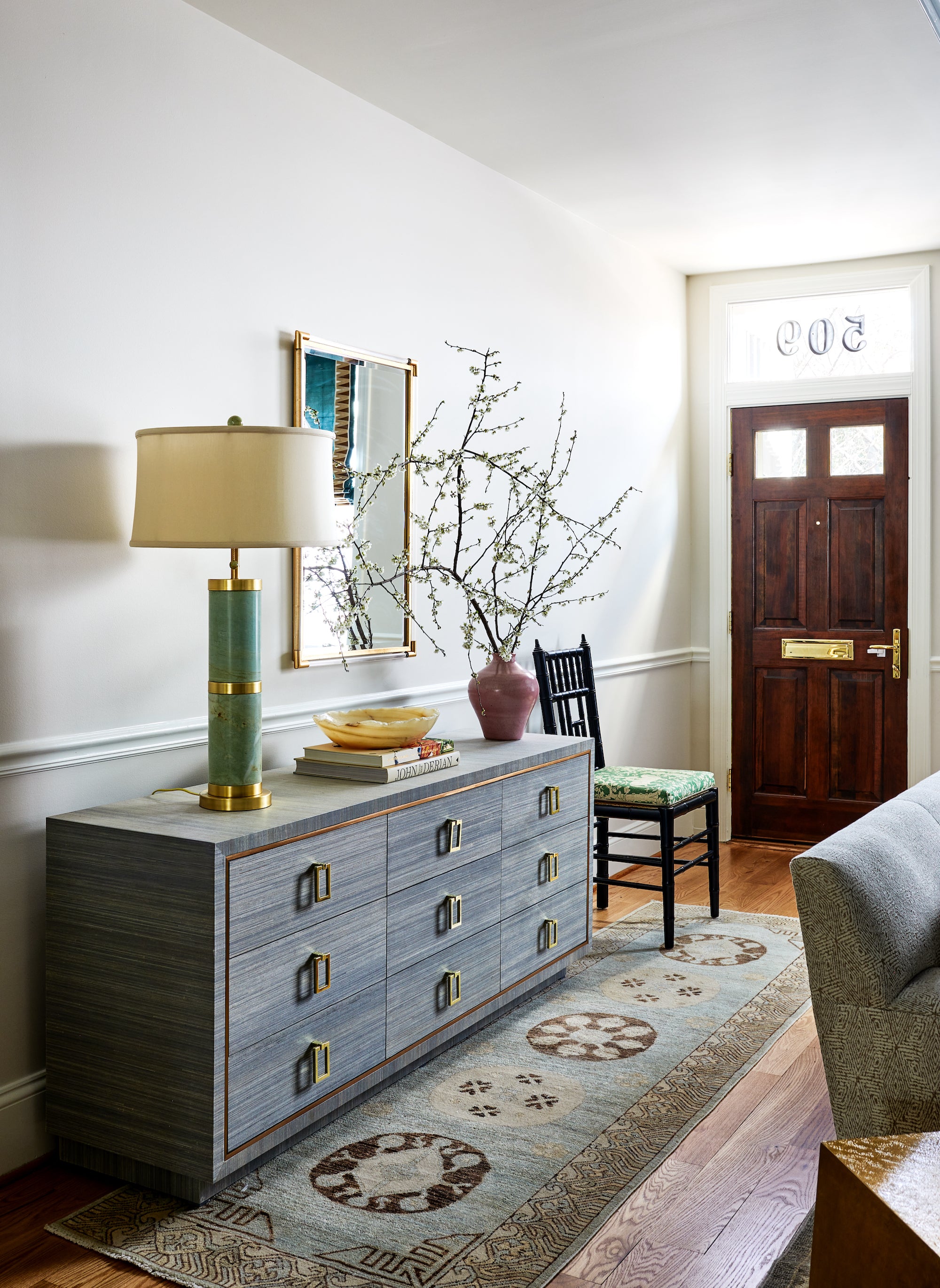 A styled entryway featuring a grey console by Lisa & Leroy.
