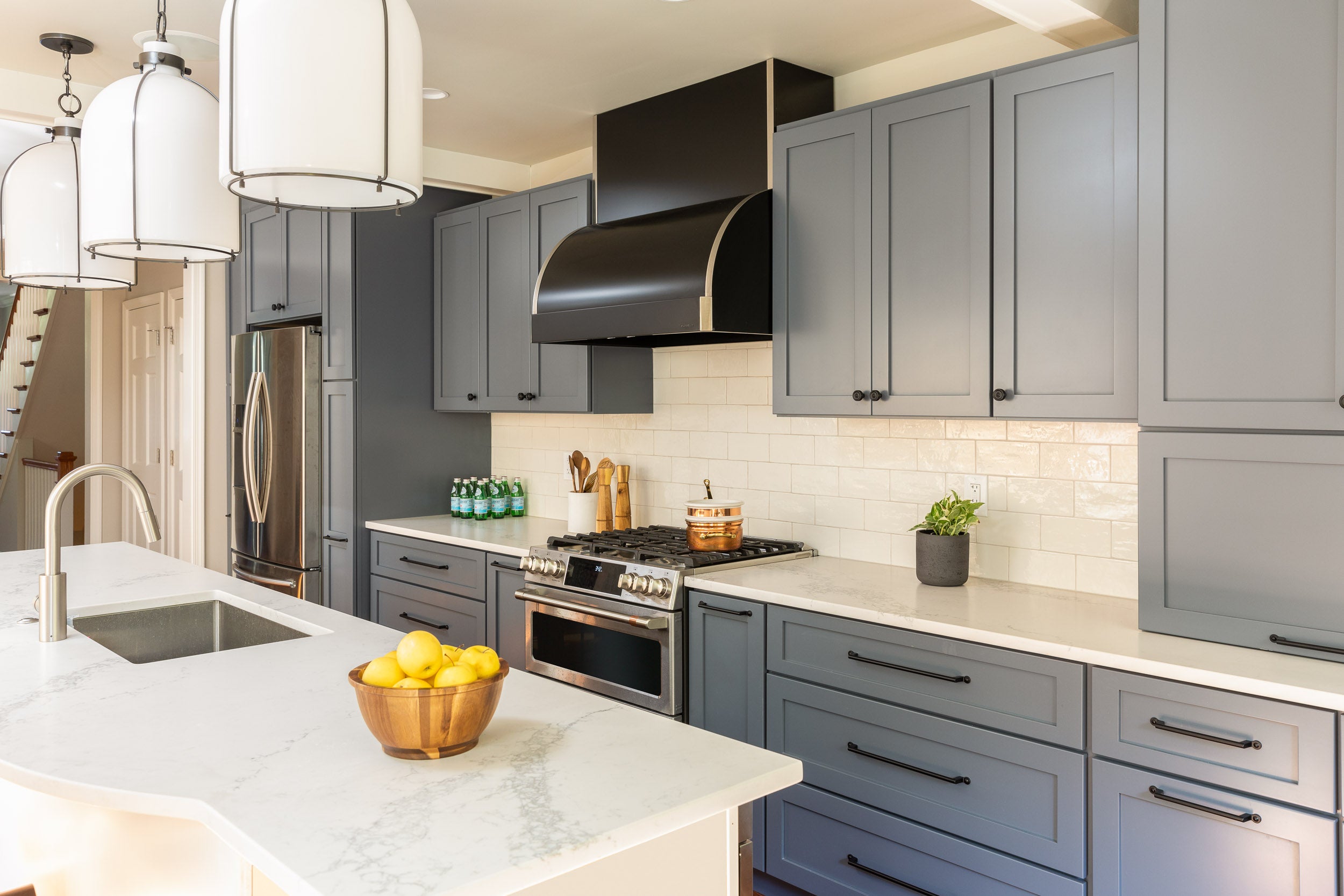 A kitchen with dusty blue cabinetry and ceramic tile by Lisa & Leroy.