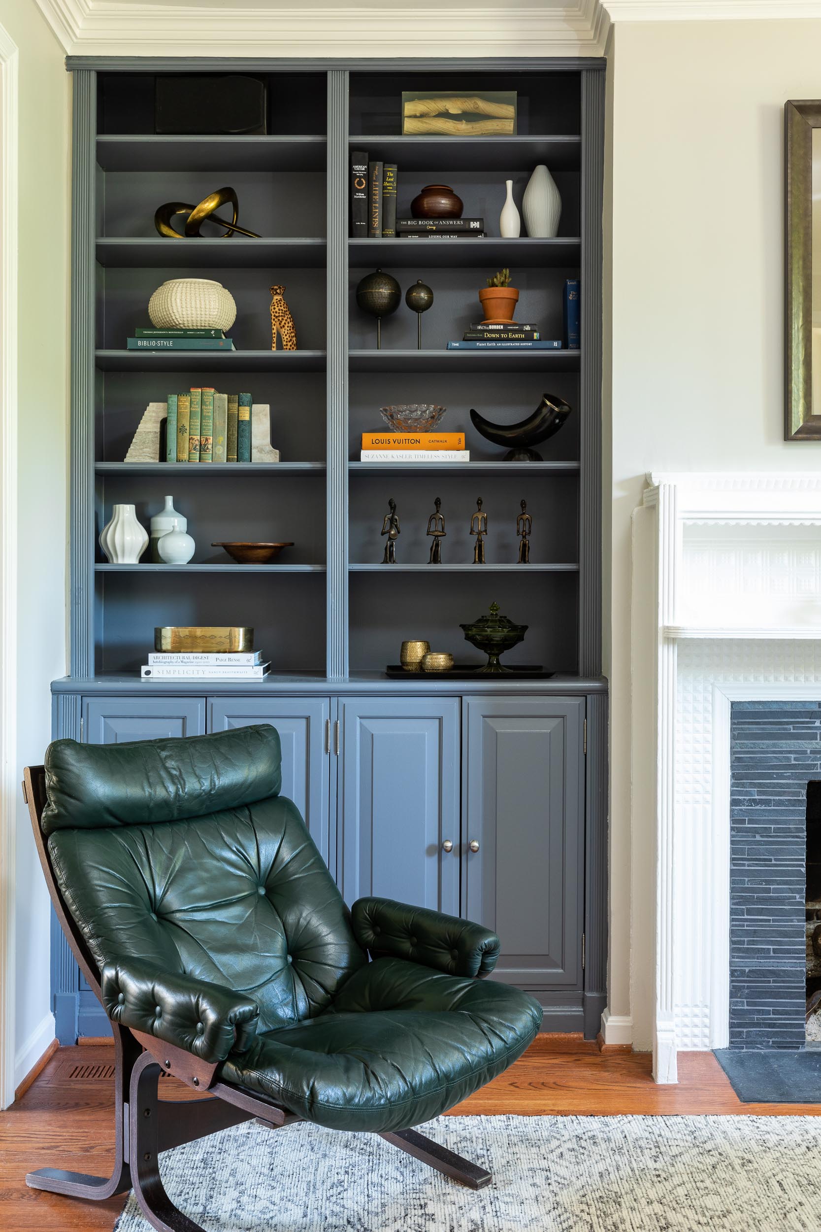 A living area by Lisa & Leroy featuring dusty blue built-ins and a vintage green lounge chair.