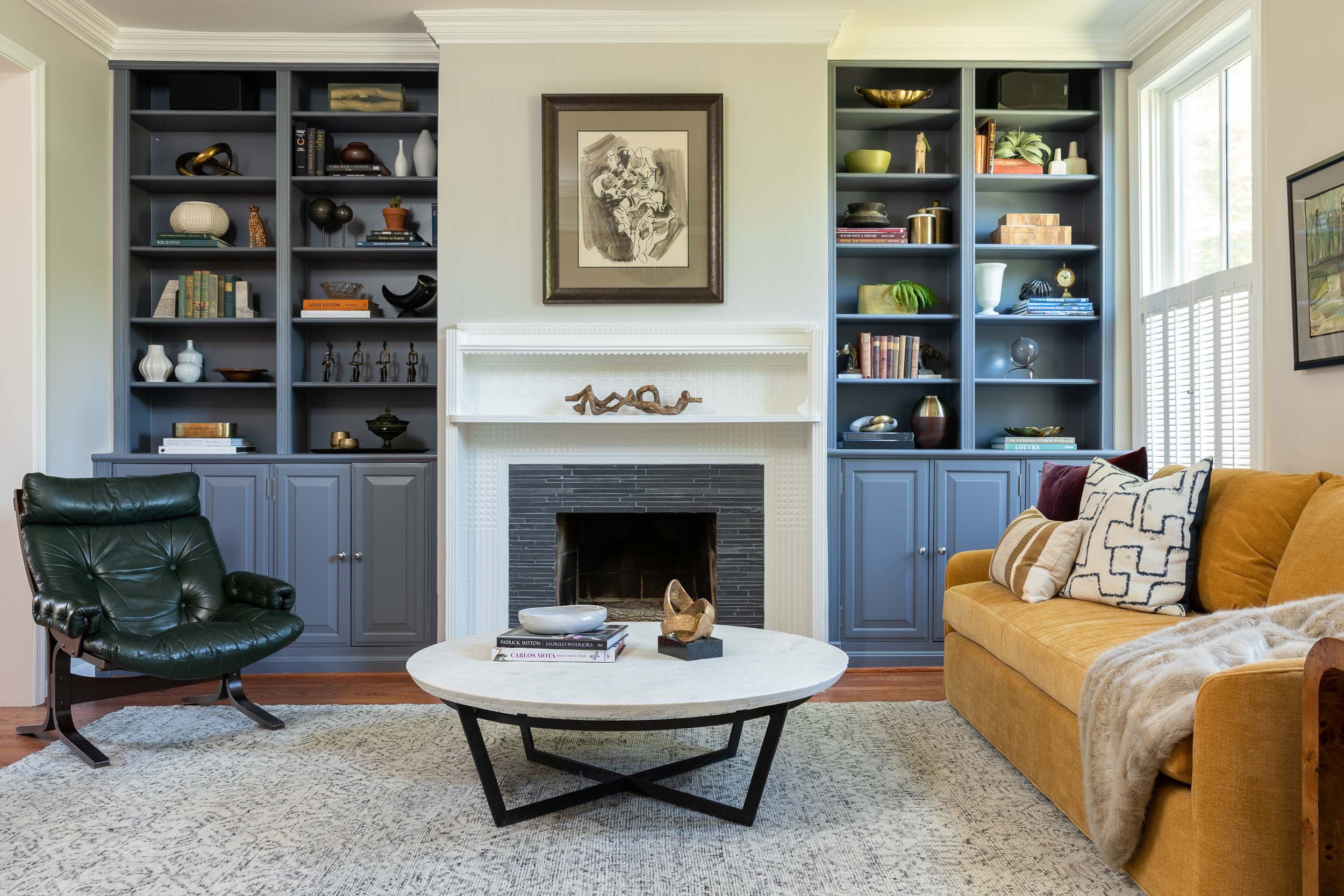 A living area by Lisa & Leroy, featuring dusty blue built-ins and a tiled fireplace.