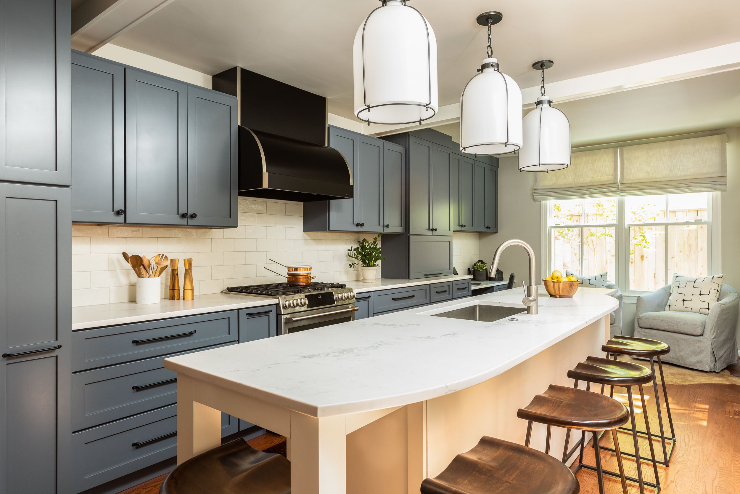 A kitchen with dusty blue cabinetry and ceramic tile by Lisa & Leroy.