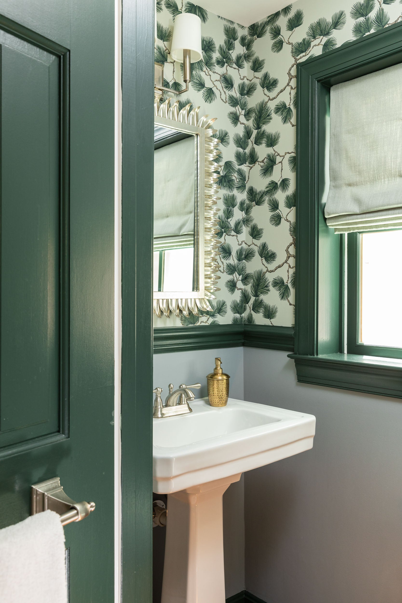 A powder bath by Lisa & Leroy with botanical wallpaper and green trim.