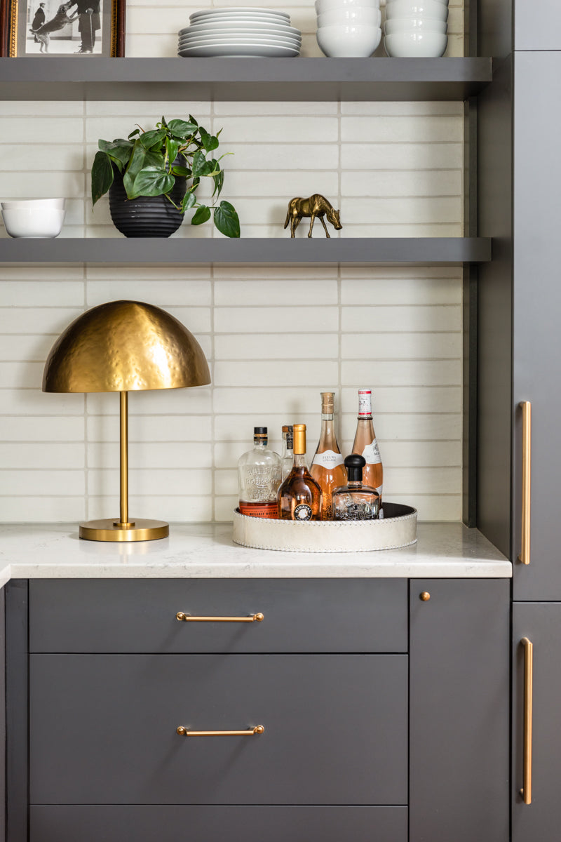 A modern gray kitchen by Lisa & Leroy with brass accents and horizontal tile backsplash.