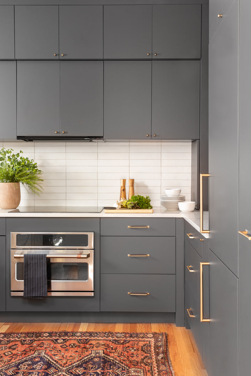 A modern kitchen by Lisa & Leroy with gray cabinetry and horizontal backsplash tiles.