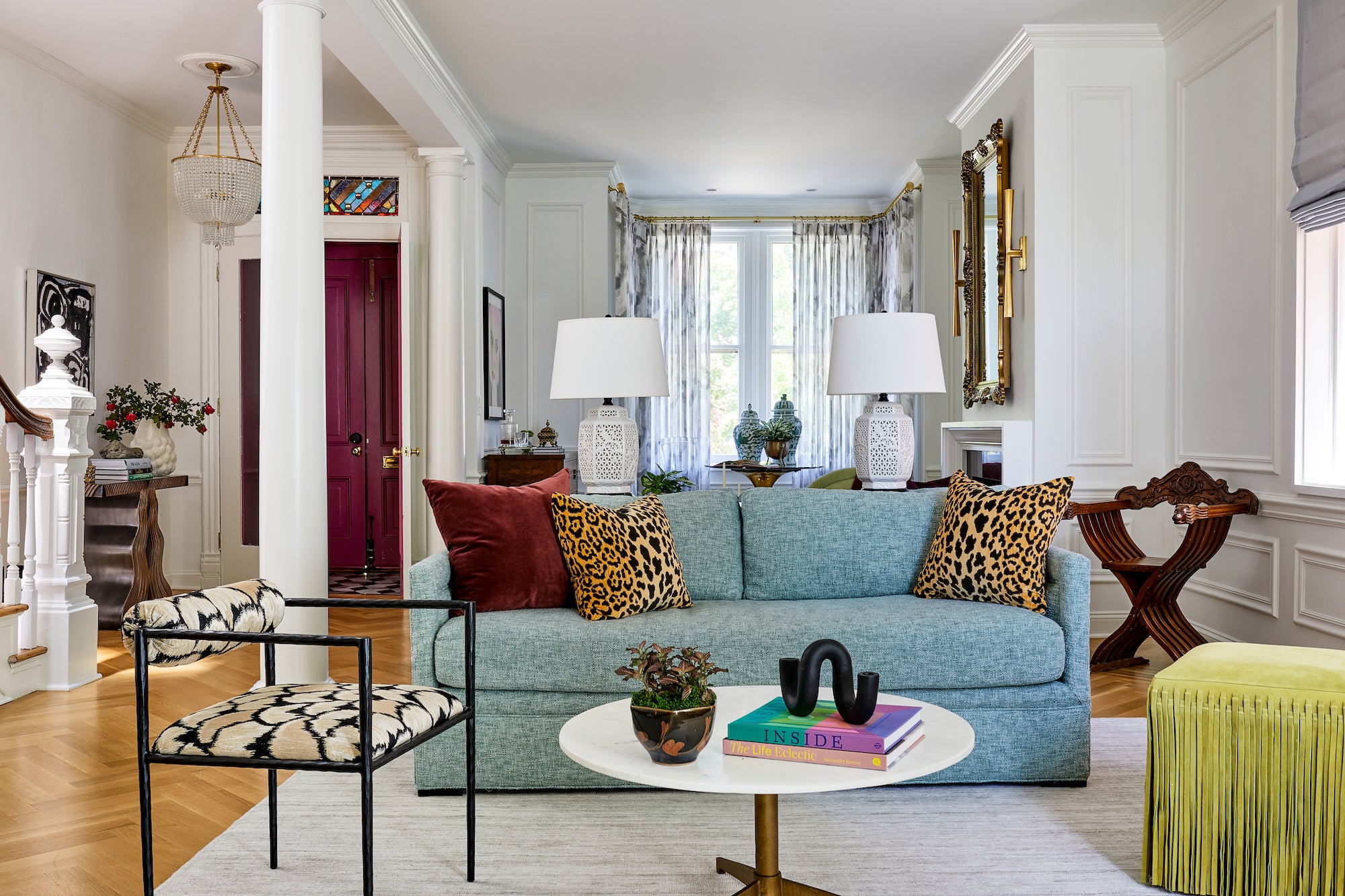 A living area with white walls, contrasted by colorful furnishings, by Lisa & Leroy.