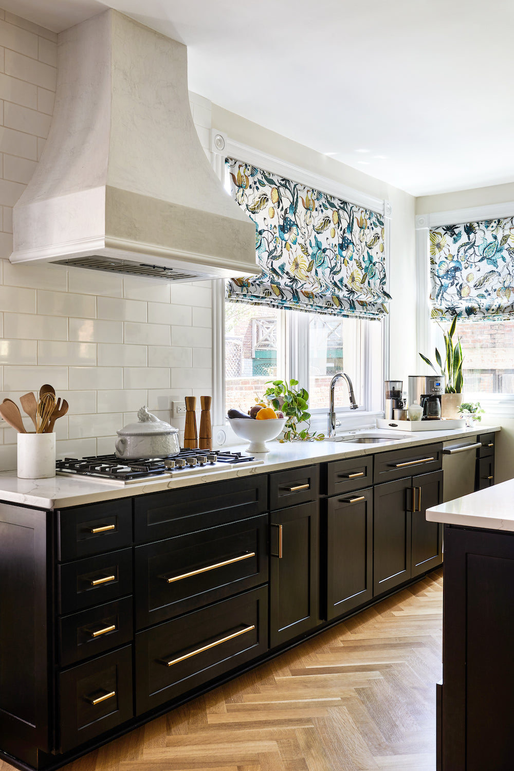 A kitchen featuring herringbone floors, black cabinetry, and ceramic tile by Lisa & Leroy.