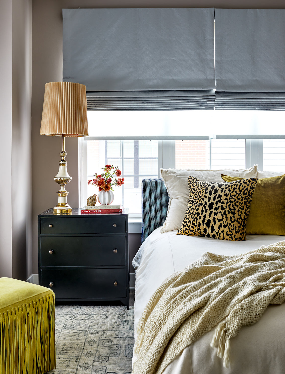 A layered and neutral bedroom with accents of animal print and chartreuse by Lisa & Leroy.