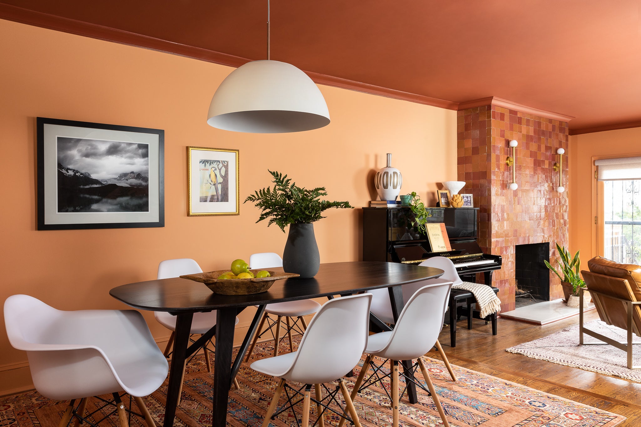 A dining area in shades of orange and rust with modern furnishings, designed by Lisa & Leroy.